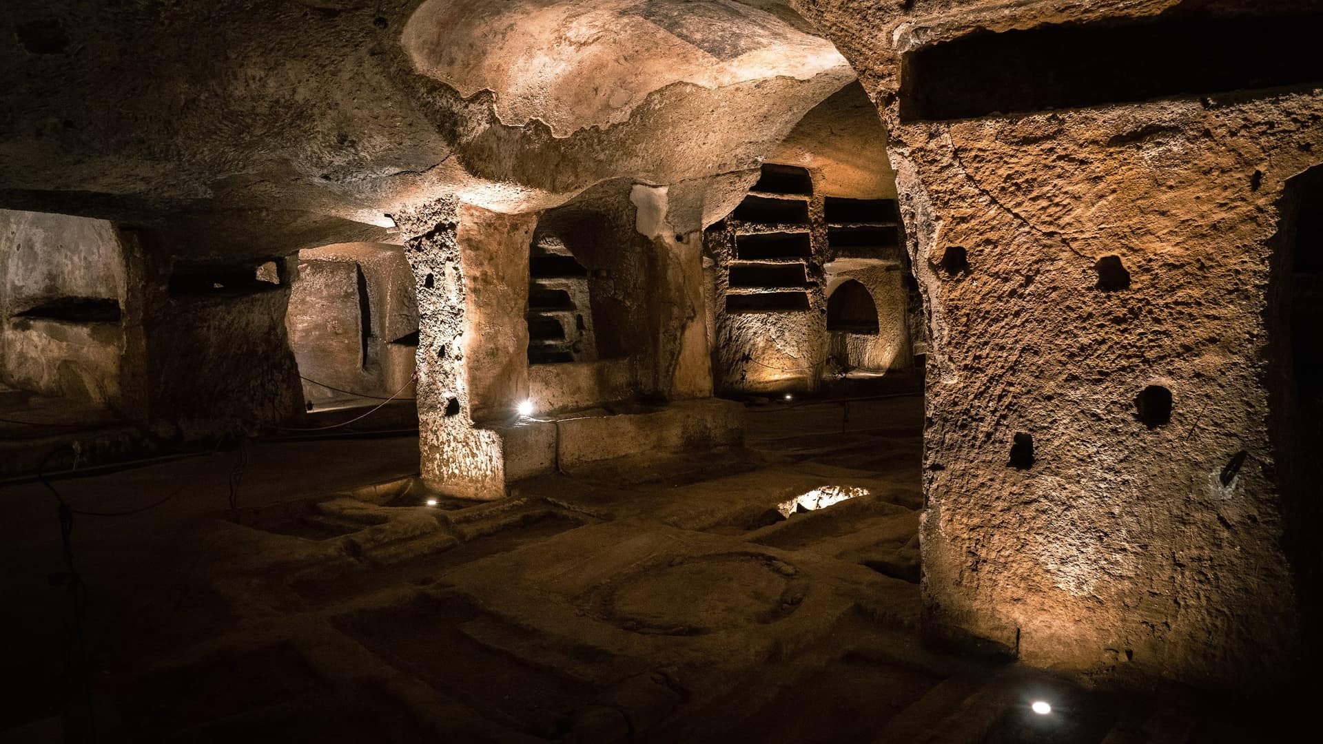 Osvětlené podzemní katakomby s kamennými sloupy