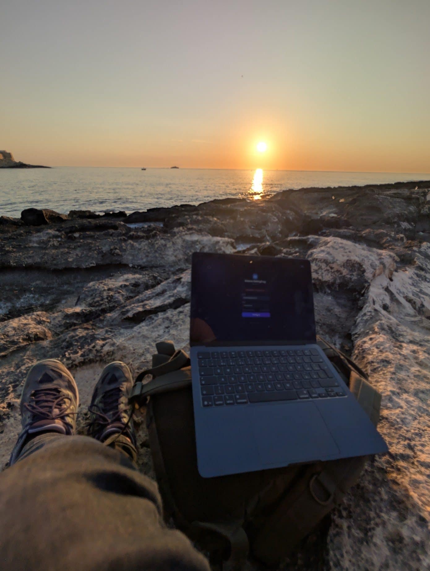 Notebook na skalnatém pobřeží při západu slunce
